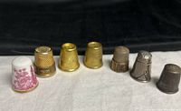 All seven thimbles lined up showing variety of materials and finishes