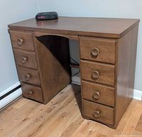 Front view of wooden desk showing eight drawers and knee space