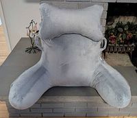 Front view of grey velour bed reading pillow with armrests and neck pillow attached