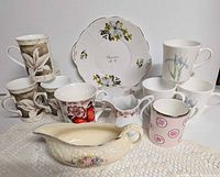 Group shot of all mugs, gravy boat, creamer and souvenir plate