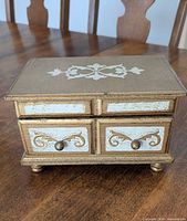 Closed wooden jewelry box showing decorative front and knobs