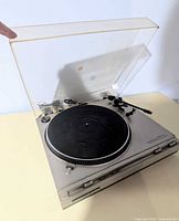 Turntable with dust cover open showing platter, tonearm and controls