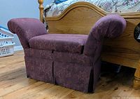 Front view of plum upholstered storage bench at foot of bed