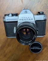 Front view of camera body with attached lens and separate lens cap