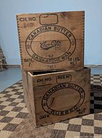 Two stacked wooden butter boxes showing Saskatchewan and Quebec stencils