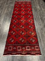Full view of red Turkman runner rug on dark floor