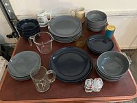 Overview of grey plates, bowls, mugs, measuring cup, glassware and shakers