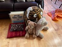 Stuffed tiger, teddy bears, foam cushion, decorative pillow on floor