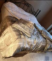 King-size bed displaying patterned comforter, folded shams, white bedspread and pillows