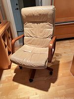 Front view of beige leather swivel chair with wood arms and base