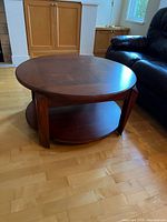 Full view of round coffee table showing top surface, lower shelf and leg design