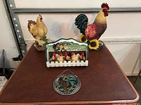 All four chicken and rooster decor pieces on table