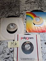 Three 45 RPM records with sleeves on countertop