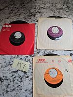 Three 45 rpm records with sleeves on countertop
