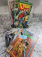 Front and rear stacks of assorted comic books with visible titles Cage and The Warlord, H5 tag included