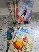 Stack of comic books on a stand showing Nightwing #100 cover