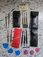 Assorted darts, cases, flights, accessories laid out