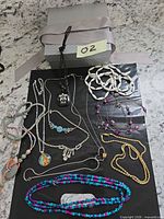 Full group shot showing all jewelry items on black surface and reference label O2