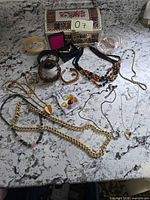 All jewelry items spread out on countertop including necklaces, bracelets, stones, memory wire and trinket box