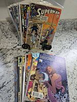 Two stacks of bagged comic books showing front covers, Superman on stand and Dominique Laveau: Voodoo Child on countertop stack