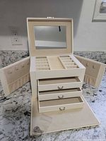 Jewelry box open showing mirror, compartments, side doors, drawers, key in bag