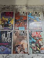 Six Outsiders comics laid out, bagged and boarded