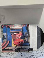 Front cover of Cyndi Lauper LP, vinyl partially removed showing black disc and white lyric sleeve