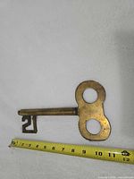 Full view of brass key with tape measure for scale