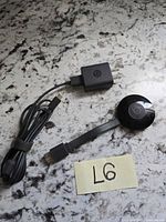 Chromecast dongle, power adapter, USB cable laid out on countertop with lot tag visible