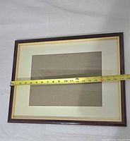 Front view of brown wood picture frame with measuring tape across width