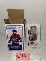 Closed box beside bubble-wrapped bobblehead and C12 tag