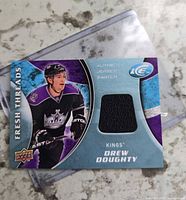 Front of the Drew Doughty Fresh Threads jersey card showing player image and black jersey swatch in sleeve
