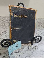 Front cover of black leather Longfellow book showing wear and detached spine