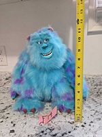 Front view of Sulley plush with tape measure showing height