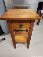 Full view of pine side table front showing drawer, shelf, legs