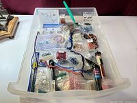 Overall view of drawer with assorted bead packets, tubes, cords, tool, and findings