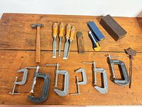Full layout of hammer, chisels, bevel gauge, utility knife, sharpening stones, C-clamps and metal rod