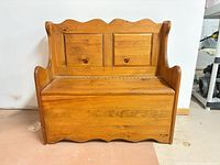 front view of wooden bench with scalloped back and storage seat