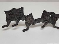 Front view of cast iron key holder showing four cat figures and hooks
