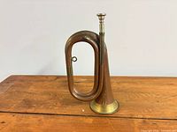 Full side view of copper bugle on wooden surface