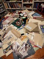 Table covered with assorted cross-stitch supplies: fabrics, patterns, floss, hoops, cutting mat