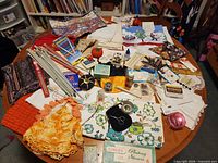 Top view of tabletop showing fabrics, knitting needles, Singer Buttonholer box, pincushion, notions and tools