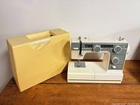 Sewing machine beside yellow hard case showing overall lot