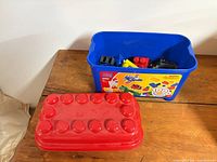 Blue Mega Bloks tub with red lid on wooden surface