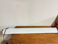 Full view of long white fluorescent grow light fixture on table