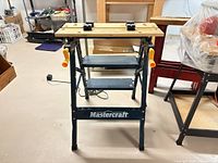 Front angle of Mastercraft folding workbench showing wooden clamping top, crank handles and frame