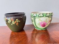 Front view of both ceramic jardinieres showing glaze colors, relief decoration and painted motifs