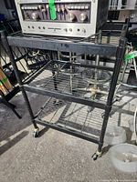 Full view of black metal three-tier rolling shelf with casters