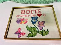 Overall view of framed needlepoint sampler in gold-tone frame