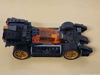 Side view of assembled LEGO Batmobile with gold wheels and orange canopy